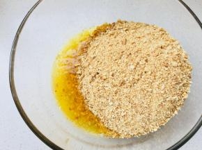 消化饼擀碎，加入到融化的黄油中。搅拌均匀。