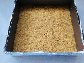 将搅拌好的消化饼随，放到慕斯圈中，用勺子将消化饼压实。放入冰箱冷藏一个小时。