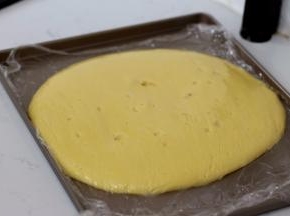 倒入不粘烤盘中，摊开后，保鲜膜贴面保存放凉备用。