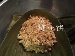再铺上糯米，把馅料盖住，将剩余叶片翻折上来包住。
