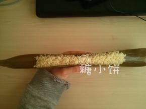 干粽叶提前用清水泡软，洗净后再用沸水烫一下。
剪去硬梗部分，取一张粽叶横着窝出一个凹槽，把准备好的糯米铺在中间。