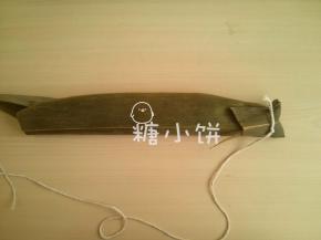 其中一端的粽叶往中间折叠，用棉绳捆住固定