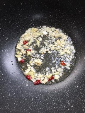 锅烧热倒入适量的油，放入生姜，蒜瓣，干辣椒爆香。