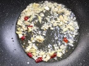 锅烧热倒入适量的油，放入生姜，蒜瓣，干辣椒爆香。