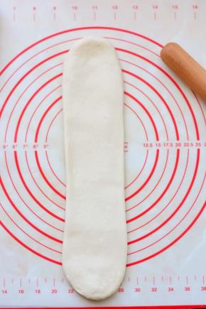 下面进行第二次擀卷，把面团再次擀面杖从中间上下擀开，成牛舌状。