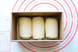 把卷好的面团排入土司盒中。