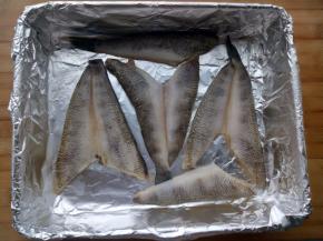 控一下水，烤盘里铺上锡纸，把腌好的冰鱼平铺在上面，烤箱200度预热10分钟后放入中层烤5分钟，然后把冰鱼取出备用。