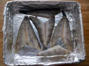 控一下水，烤盘里铺上锡纸，把腌好的冰鱼平铺在上面，烤箱200度预热10分钟后放入中层烤5分钟，然后把冰鱼取出备用。
