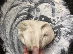 操作台上撒上干粉，拿出发酵好的面团，按压排气