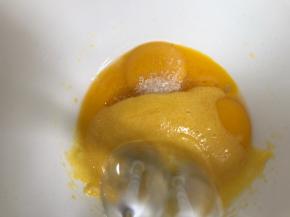 把剩下的糖放入蛋黄中，启动打蛋器低档打至糖融化，加入牛奶和玉米油，搅拌均匀