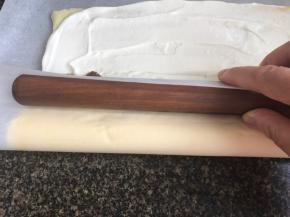 用擀面杖托起油纸，并慢慢把油纸卷起，对向的把蛋糊体向里卷成卷