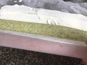 用擀面杖托起油纸卷住擀面杖，对向把蛋糕向里卷成卷，再把两头不规则的部位切去