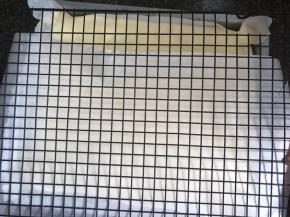 拿出烤好的蛋糕，盖上一层油纸，再盖上凉网，翻过来，拿下烤盘，放置冷却