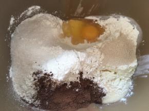 先来做可可面团，将高筋面粉，奶粉，炼乳，鸡蛋，可可粉，细砂糖跟酵母加入到面包桶内