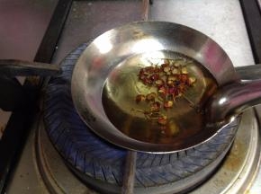 炒勺里倒入植物油，冷油加入几粒花椒小火炸制变色关火