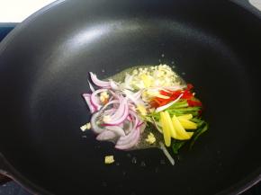 5，油锅烧热，放入葱姜蒜、青红椒和洋葱爆炒一小会。
