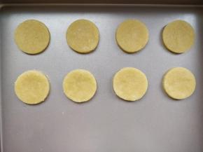 将一块黄油饼干面团擀成厚3mm的片，用模具扣出直径约4cm的圆片，放在不粘烤盘上，中间留出稍宽的位置。黄油饼干配方和制作方法，请见“柠檬摩天轮饼干”。