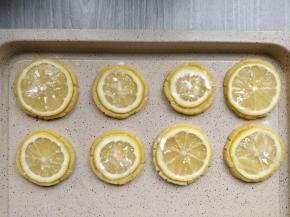 烤箱预热，上下火180度，同时将2个柠檬切成厚度约2mm的片，用毛刷将另一半全蛋液刷在饼干上，再把柠檬片放在饼干顶部，撒上糖粉。