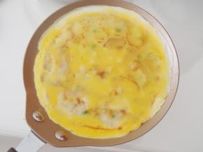 一面煎熟后翻面，磕上适量打散的鸡蛋