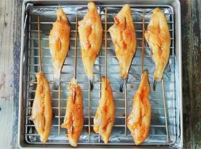 备一个学厨烤盘和烤架，把串好的冰鱼码放在烤架上，再刷上点腌料