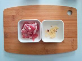 将猪肉放入淘米水中浸泡20分钟，浸泡可以使猪肉中的细菌和血水全部去除，再用流动的清水清洗干净并切成薄片，并加入少许生粉和植物油搅拌均匀，腌制10分钟左右；蒜瓣拍碎去壳，切成蒜蓉备用