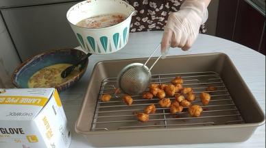 炸好的鸡米花捞出放在滤油盘里。