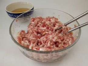 趁着发面团的时间，我们把馅料处理一下。
先把猪肉、姜末放入碗中拌匀，然后再分多次打入花椒水(俗话说得好，要想香得多加姜，打入花椒水的时候，一定要每次少量的倒入，顺时针搅拌上劲吸收后，再加入下一次)。