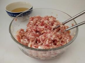 趁着发面团的时间，我们把馅料处理一下。
先把猪肉、姜末放入碗中拌匀，然后再分多次打入花椒水(俗话说得好，要想香得多加姜，打入花椒水的时候，一定要每次少量的倒入，顺时针搅拌上劲吸收后，再加入下一次)。