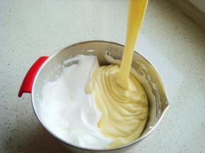 把打好的蛋白分一半倒入蛋黄糊糊里。呈“J”字形翻拌，不可划圈避免消泡。