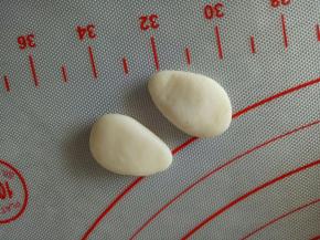 取2个分别是2克的面团，揉成水滴状，稍微按扁，做兔子的手部