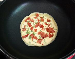 趁着面糊没有凝固的时候，均匀地撒上一层培根。