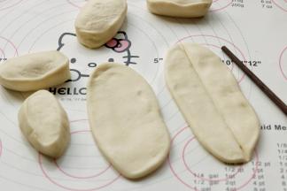 把面剂子揉圆搓长成柱状，按扁，然后再擀开成为椭圆的面片，不需要擀太薄，然后用筷子在中间按一下，按出一个压痕，这是为了拉开时候可以从中间轻易分开成两根，避免面条太宽。