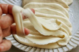 准备煮面条，先把汤锅加上水烧开。醒发之后的面片很容易就能拉开，两手扯着拉长拉薄，再从中间分开成为两根面条，然后下入锅里煮。