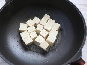 不粘锅中倒入适量食用油，放入豆腐块，小火煎一下。