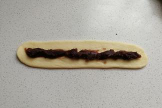 然后把长条状擀成扁平的长条片，再在长面片中间放上适量豆沙馅，把豆沙馅也整成长条型。