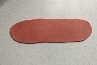 再取一份红面团，先搓成圆柱状，再擀成较宽的长舌状。