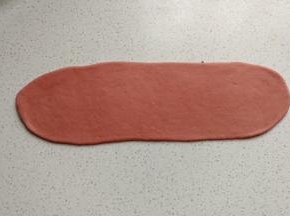 再取一份红面团，先搓成圆柱状，再擀成较宽的长舌状。