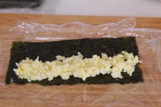 放入少许蛋黄米饭，借助保鲜膜卷起