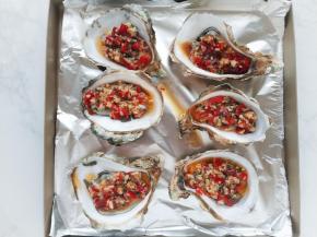 将生蚝铺在烤盘上，用汤匙将调味料淋在生蚝上。