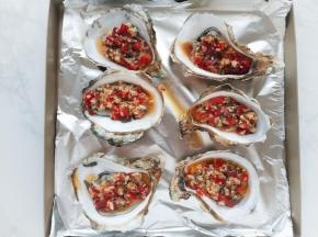 将生蚝铺在烤盘上，用汤匙将调味料淋在生蚝上。