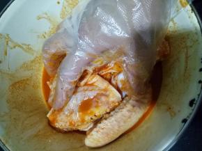 将鸡翅倒入，戴一次性手套抓捏均匀，让每一个鸡翅都裹满调料，盖保鲜膜放冰箱腌制大约10小时，前天早上腌制，第二天早上做正好