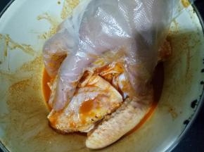 将鸡翅倒入，戴一次性手套抓捏均匀，让每一个鸡翅都裹满调料，盖保鲜膜放冰箱腌制大约10小时，前天早上腌制，第二天早上做正好
