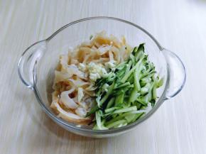 将黄瓜丝和海蜇皮丝放入玻璃器具中，加入切好的蒜。