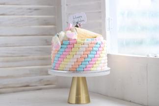 在蛋糕上面摆放好冰淇淋桶，挤上奶油，摆放好爱心棉花糖和糖珠