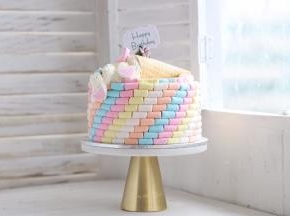 在蛋糕上面摆放好冰淇淋桶，挤上奶油，摆放好爱心棉花糖和糖珠