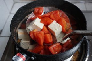 将番茄和豆腐捞起，倒去水，将番茄豆腐放回锅里