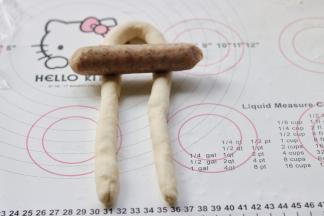 搓好的长条，对折起来，在大约三分之一处放上火腿肠。靠近对折的那头三分之一处。用了两种香肠，其中有两根略微粗的是儿童香肠，其余颜色较深的是台湾风味的烤肠。