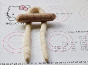 搓好的长条，对折起来，在大约三分之一处放上火腿肠。靠近对折的那头三分之一处。用了两种香肠，其中有两根略微粗的是儿童香肠，其余颜色较深的是台湾风味的烤肠。