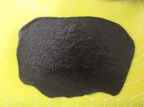 之后翻个面，将光滑的一面朝下，这样一会卷起来的时候光滑的一面就在表层，之后再用擀面杖将底下部分擀薄，这样一会卷起来的时候能够很好的粘在一起