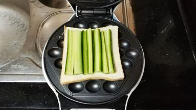这是电铛板做的：在鸡蛋仔电铛机上放一片吐司，再放入青瓜条（或生菜）